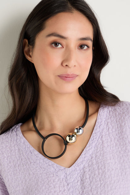A woman with long dark hair wears a textured lavender top and the Space Necklace, which features oversized acrylic beads, as she stands against a light background.