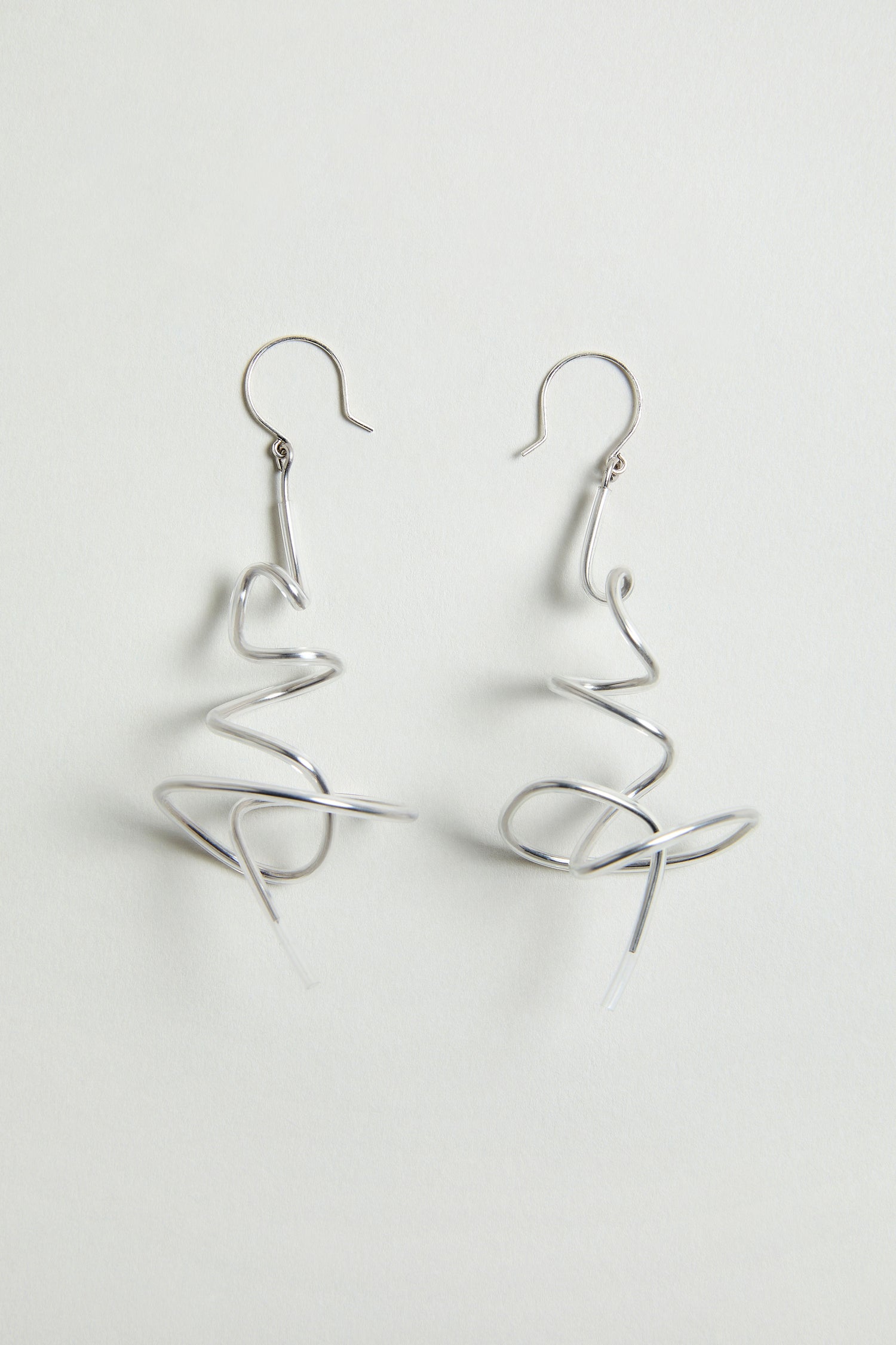 The Squiggle Earrings feature an abstract twisted silver design, showcasing contemporary style. Displayed against a plain white background.