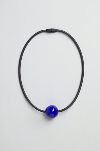 The Murano Bead Necklace is a minimalist, handmade piece from Paris with a single glossy blue bead on a black cord, shown against a plain light background.
