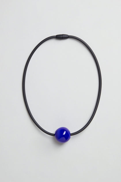 The Murano Bead Necklace is a minimalist, handmade piece from Paris with a single glossy blue bead on a black cord, shown against a plain light background.