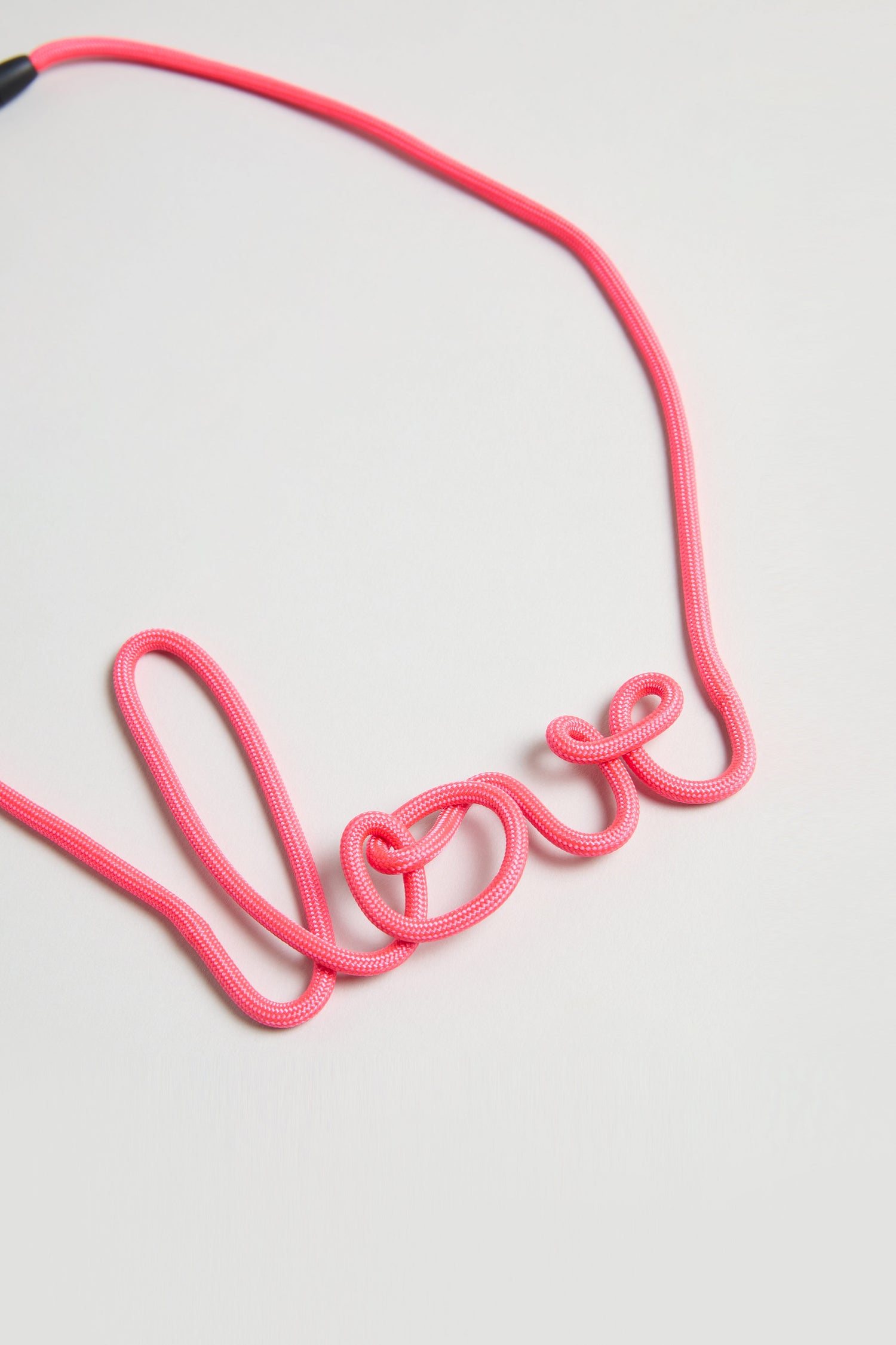 A pink cord forms the word "love" in cursive on a light background, showcasing the enchanting handmade design of the Love Necklace.