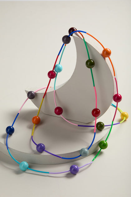 A three-dimensional metal model of an atom with Rainbow Sphere Colour Pop Necklace representing electrons.