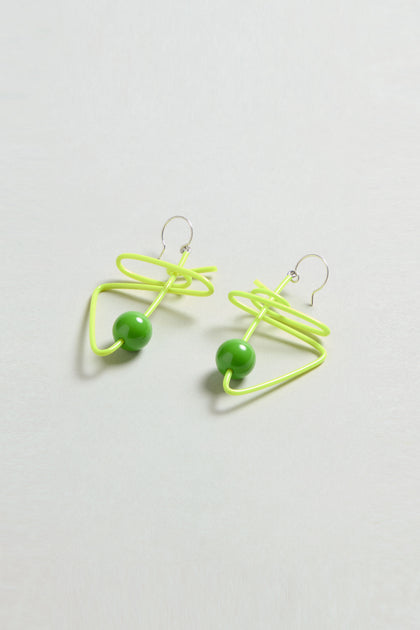 The Doodle Earrings feature neon yellow wire loops and green beads by Samuel Coraux, displayed on a light background.