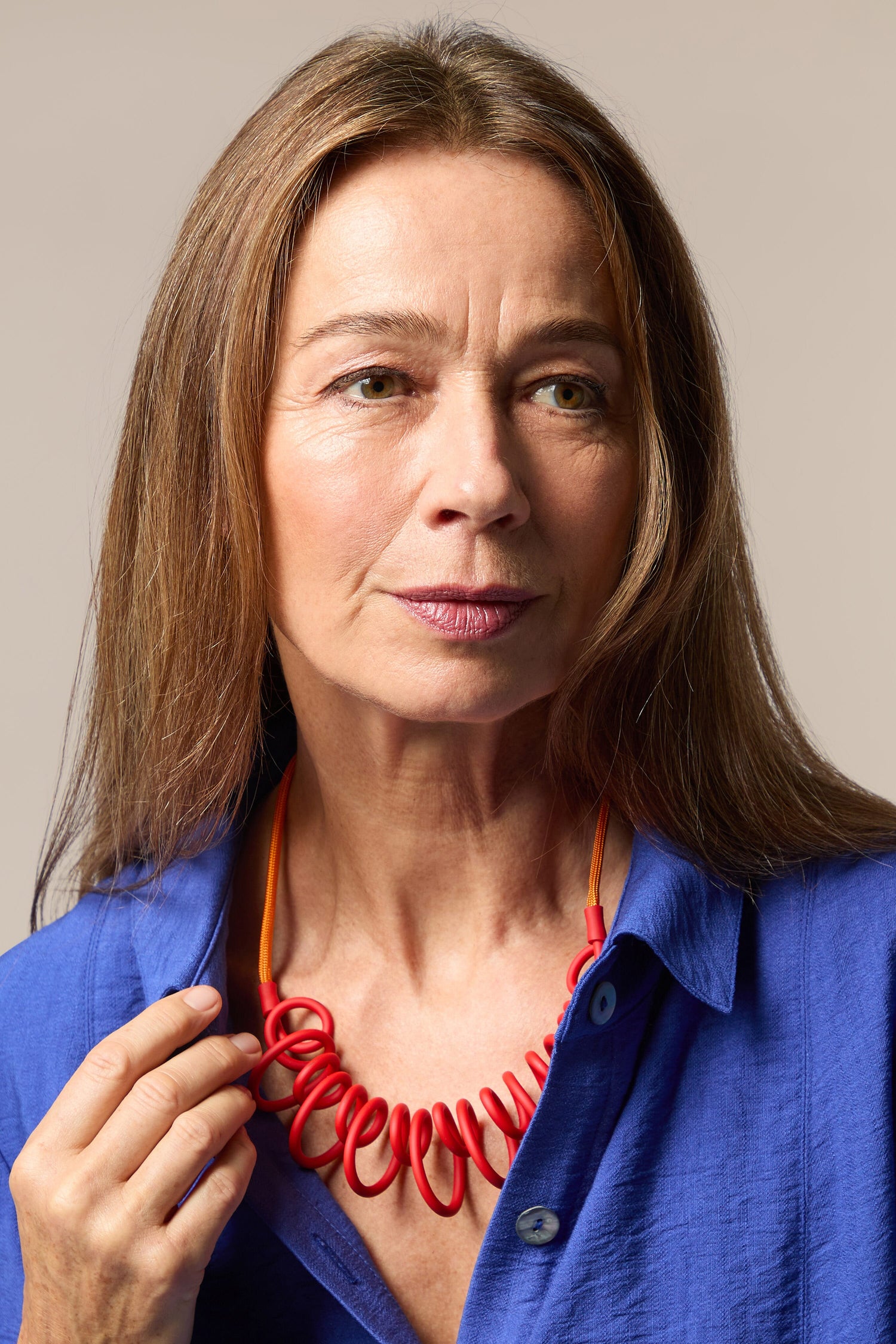 A woman in a blue shirt adorned with a contemporary Citrus Squiggle Necklace.