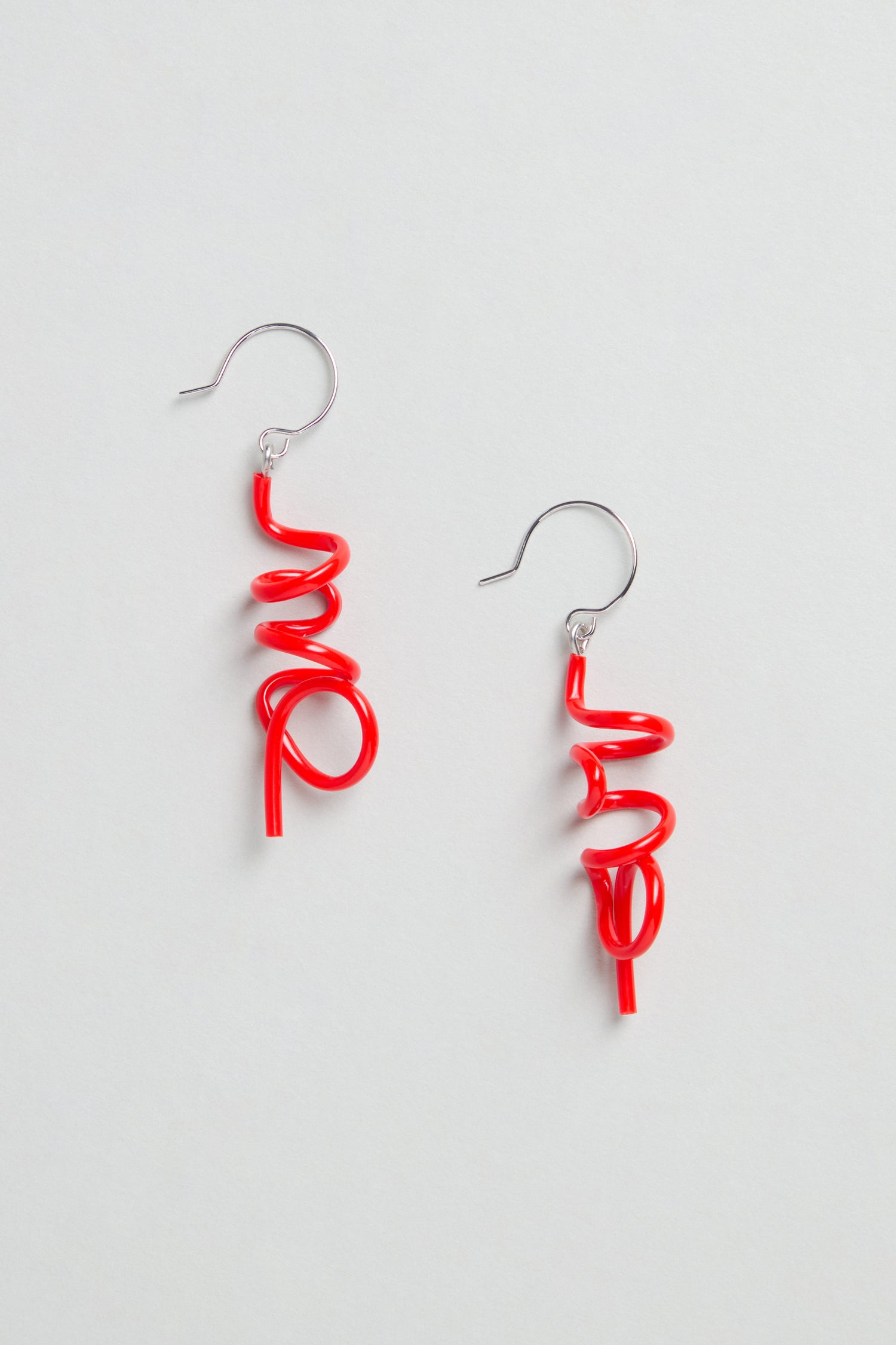 The Mini Sketch Earrings, handmade in Paris, feature red spiral-shaped dangles and silver hooks, shown on a plain white background.