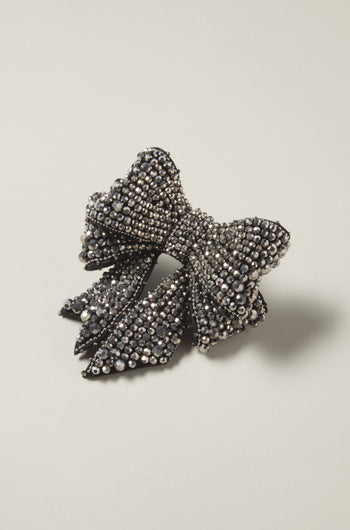 A refined Bow Brooch in elegant black, decorated with shimmering silver rhinestones, is beautifully displayed against a light gray background, embodying sophisticated style.