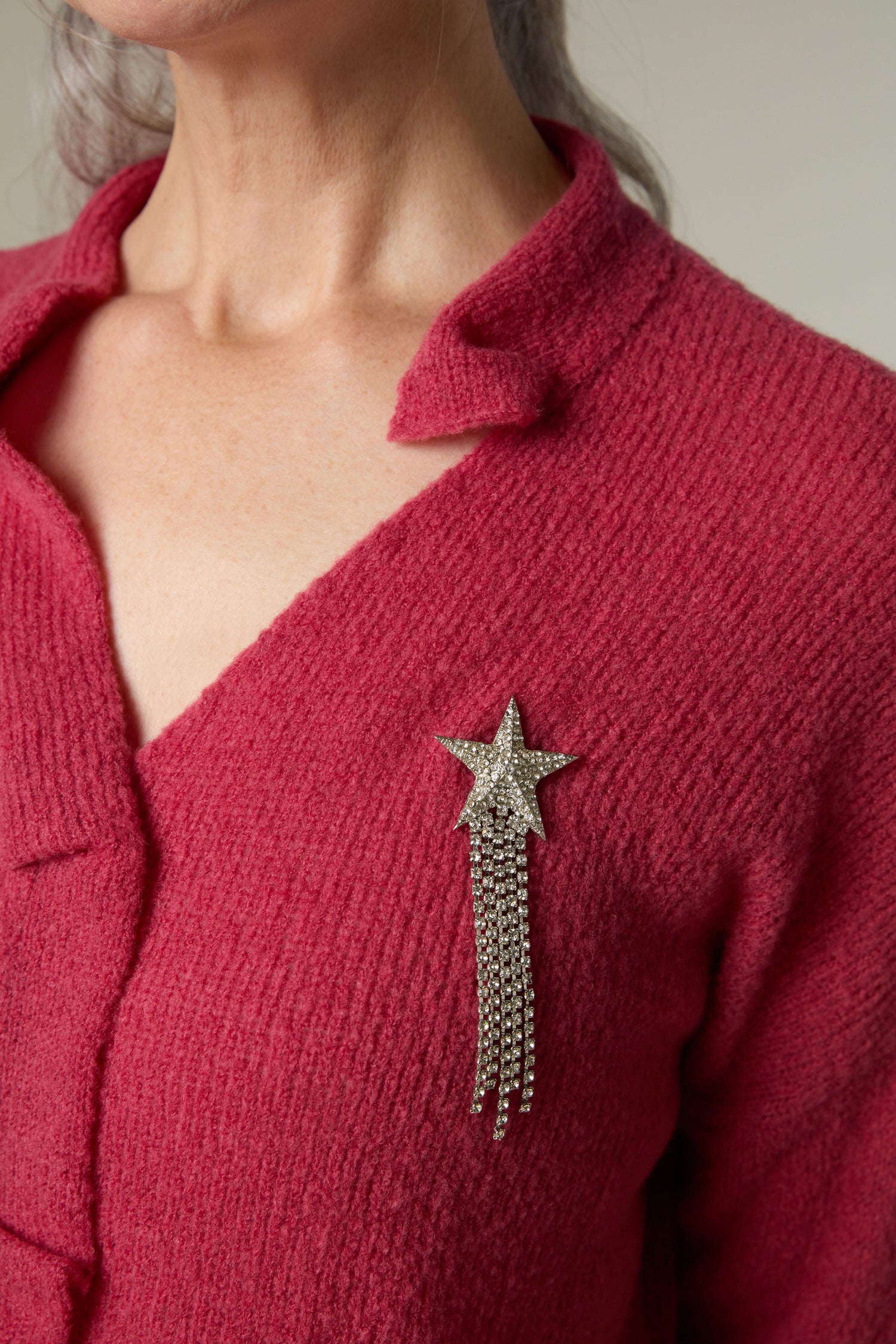 A woman wearing a red sweater with a Shooting Star Brooch.