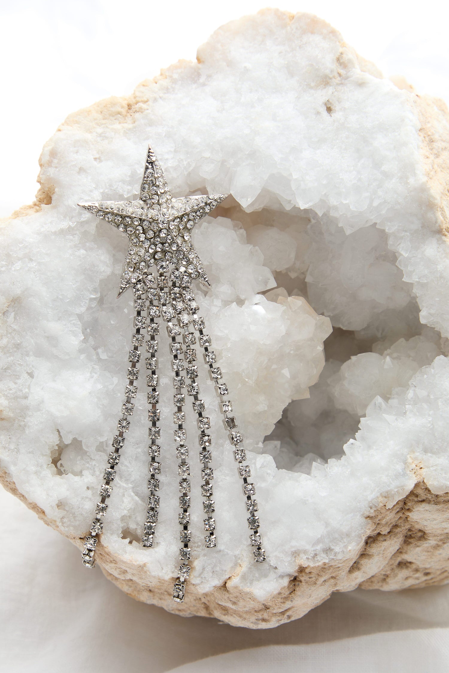 A Shooting Star Brooch with sparkling diamantes and pin fastening on a rock.