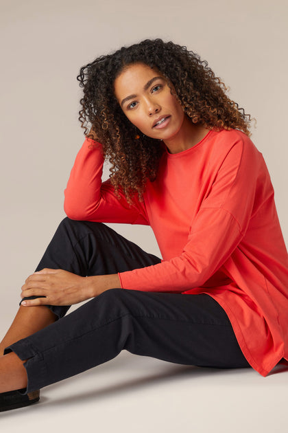 A woman wearing a comfortable Cotton Jersey Relaxed Top from her wardrobe, sitting on the floor.