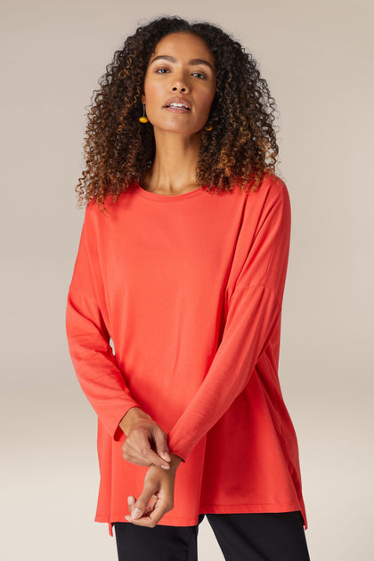 The comfortable long sleeved Cotton Jersey Relaxed Top in red is worn by a woman.