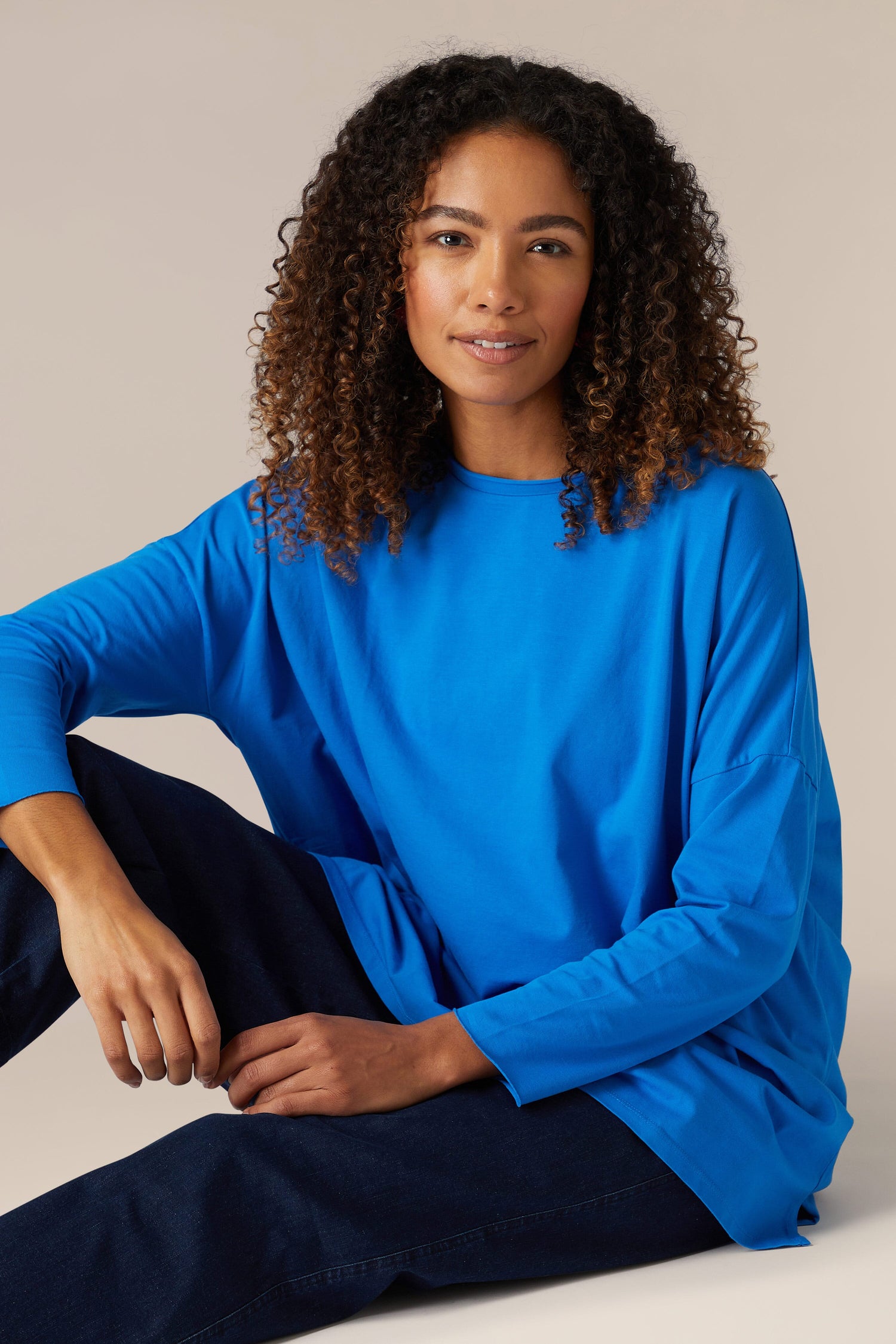 A woman is sitting on the floor in a comfortable Cotton Jersey Relaxed Top.