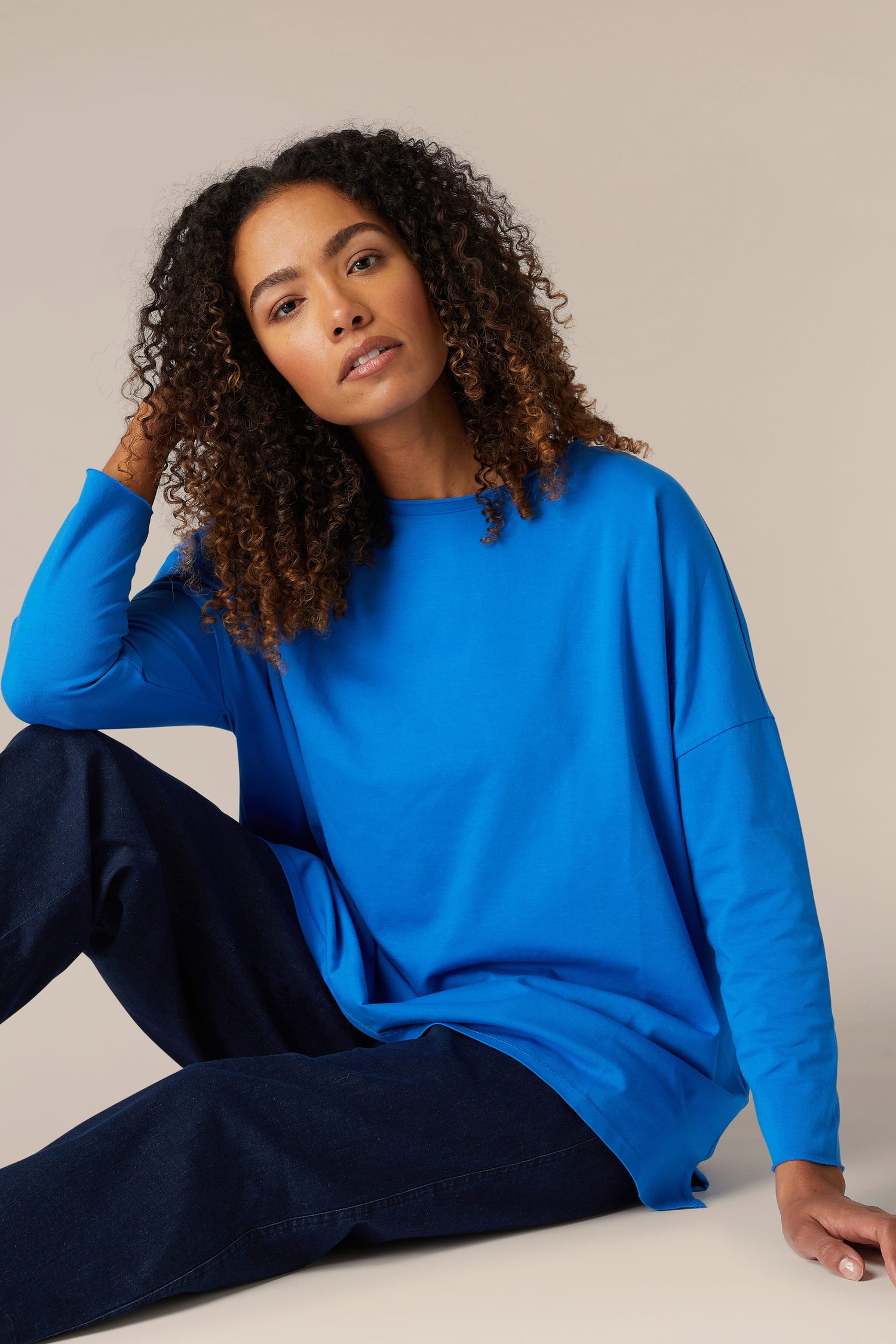 A woman is sitting on the floor in a comfortable Cotton Jersey Relaxed Top.