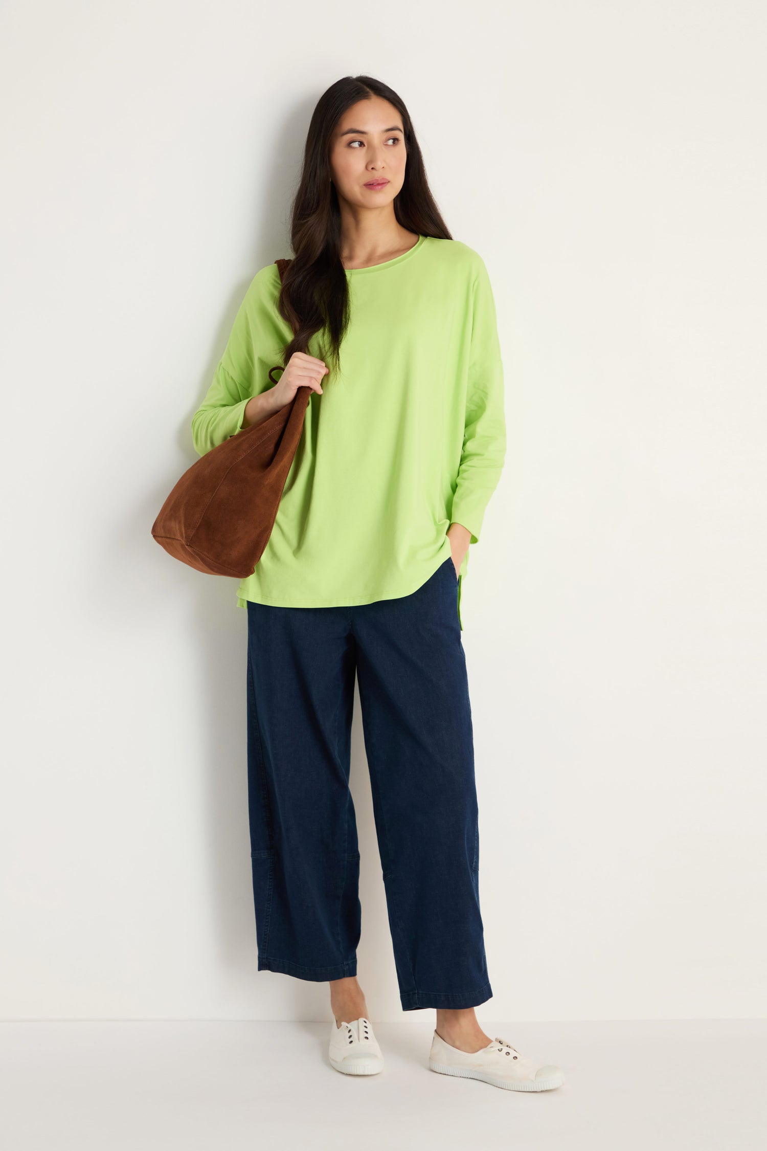 A woman wears a green Cotton Jersey Relaxed Top and blue pants.