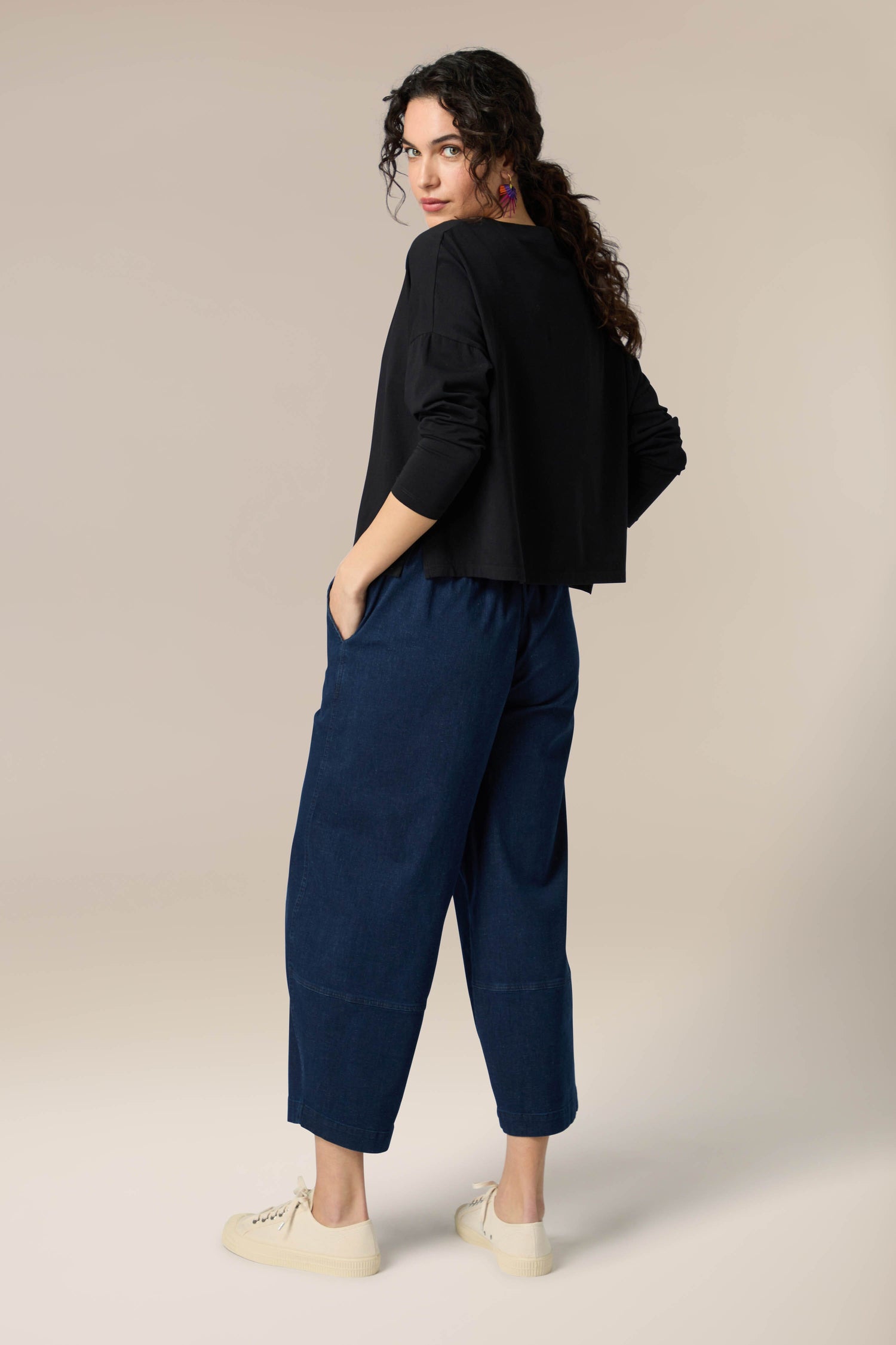 The woman's back view showcases a versatile Cotton Jersey Drapey Top paired with denim pants.