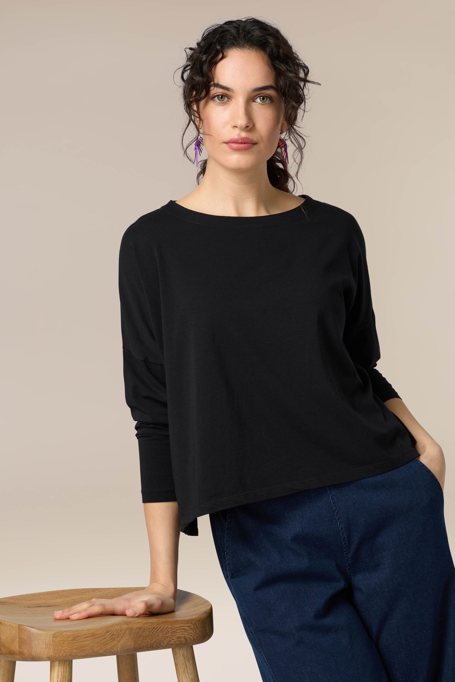 A woman wearing a Cotton Jersey Drapey Top, a versatile black long-sleeved top.