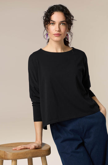 A woman wearing a Cotton Jersey Drapey Top, a versatile black long-sleeved top.