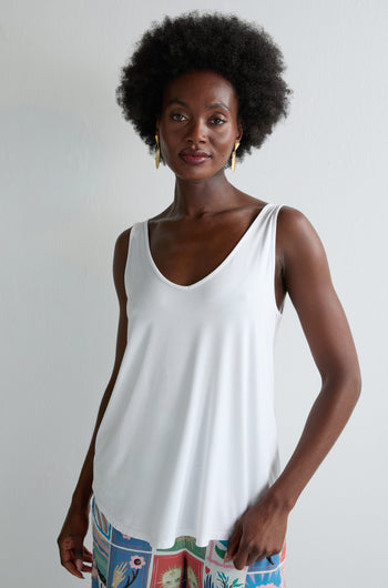 A woman with an afro hairstyle wears the Viscose Jersey V Neck Vest and colorful patterned pants, perfect for summer, standing against a plain light-colored background.
