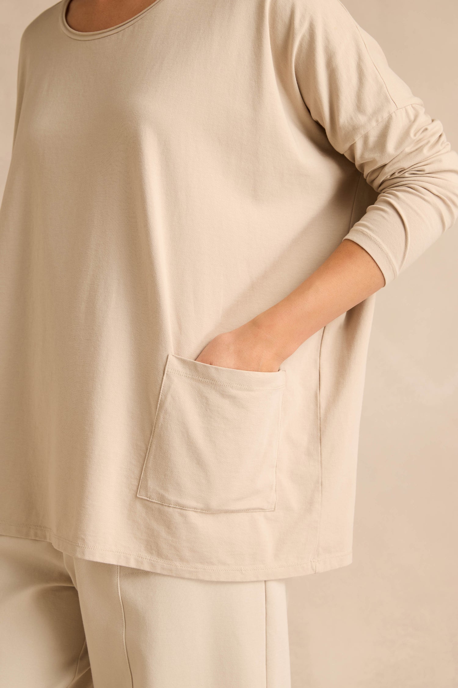 A person wearing the Ecru Cotton Jersey Pocket Top with one hand in the front pocket; image is cropped to show only the torso and arm.