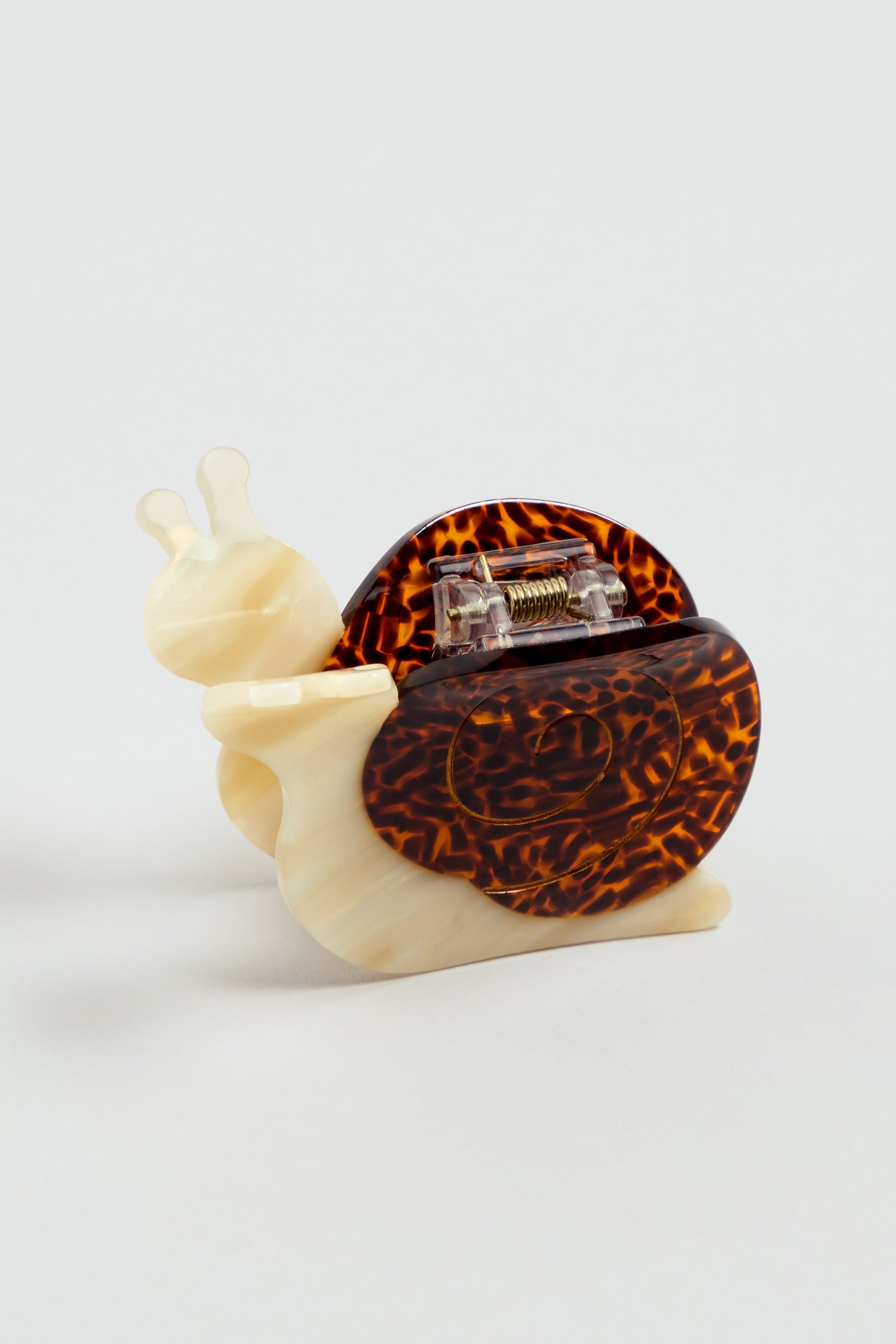 The Hand-painted Snail Hair Clip, featuring a cream body and brown speckled shell made from eco-friendly cellulose acetate, is displayed on a simple light background.