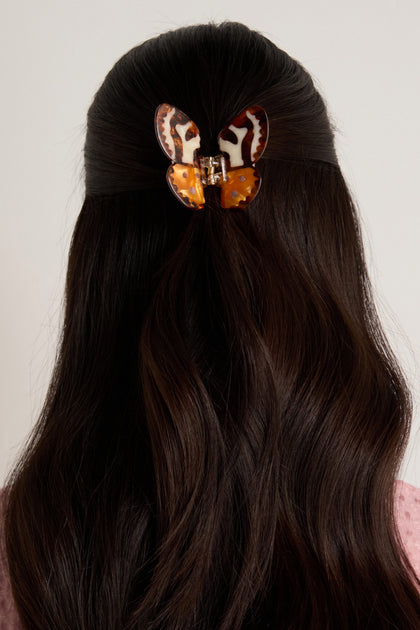A person with long, dark hair styled half-up, secured with the Hand Painted Tiger Moth Hair Clip.