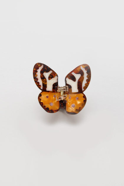 The Hand Painted Tiger Moth Hair Clip is an eco-friendly, butterfly-shaped accessory with brown, orange, and cream marbled patterns set against a plain white background.