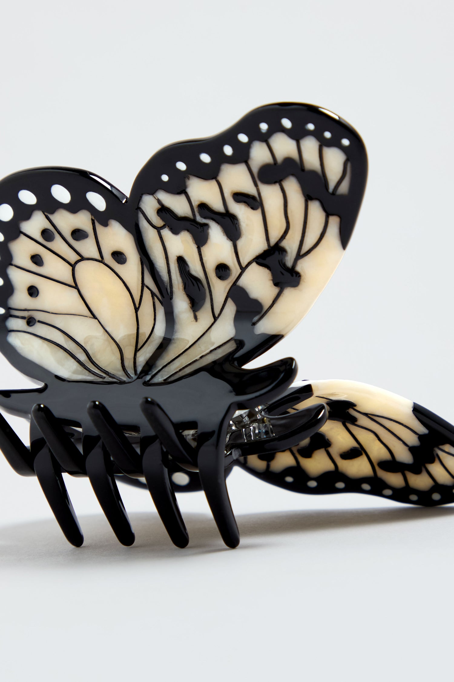 A close-up of the Hand-Painted Kite Butterfly Hair Clip in black and cream, showing detailed wing patterns against a plain light background.