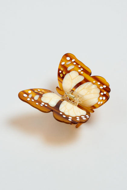 The Hand-painted Monarch Butterfly Hair Clip features brown and cream wings with white spots, offering an eco-friendly accessory for a natural, elegant look. Set against a plain light background for added charm.