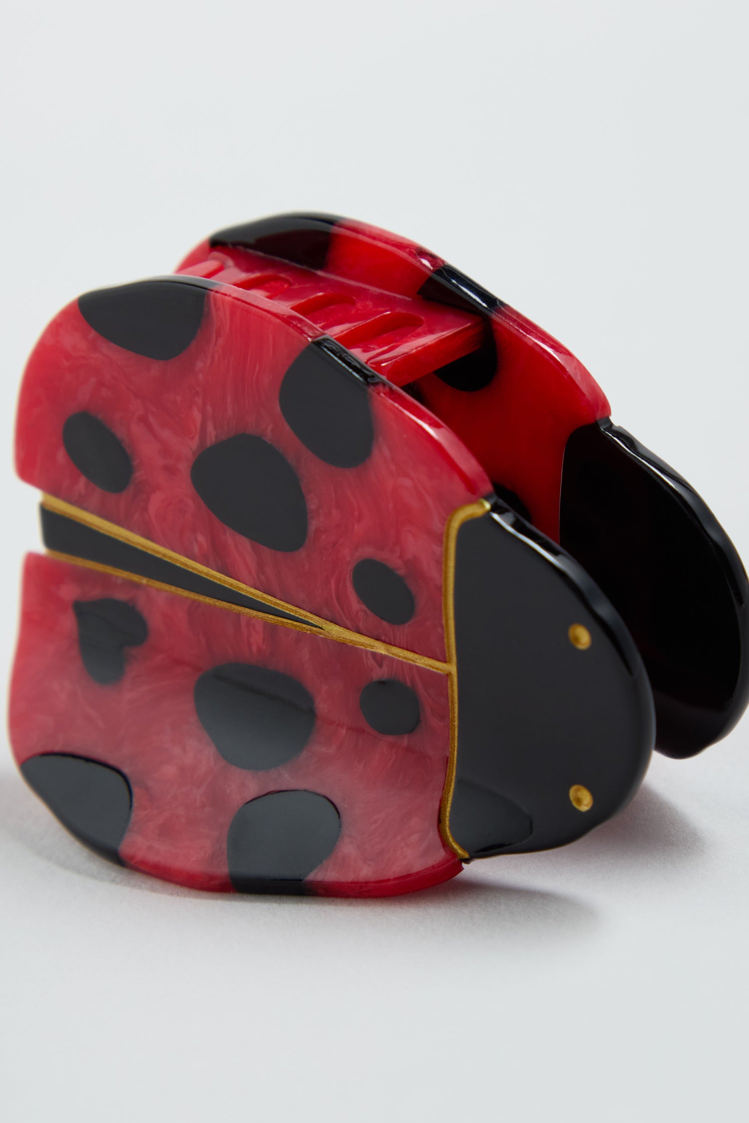 The Hand-Painted Ladybird Hair Clip features a red and black ladybird with yellow outlines, set against a plain light background.