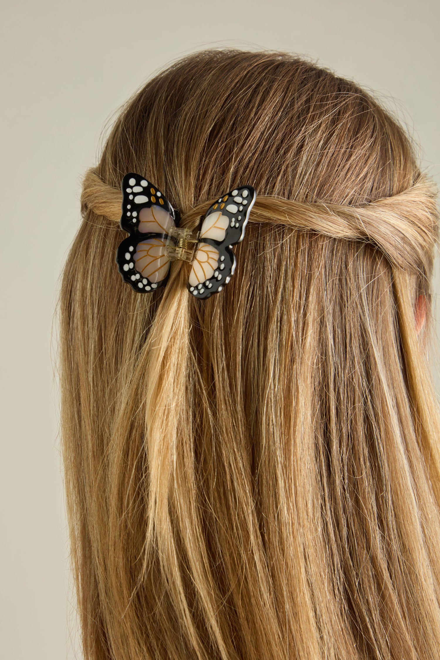 The hair is styled in a twisted half-up fashion, adorned with the Hand Painted Mini Monarch Hair Clip crafted from biodegradable acetate at the back.