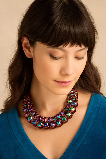 A woman wearing a Velvet Ribbon Statement Necklace featuring dark, iridescent crystals set in a velvet ribbon.
