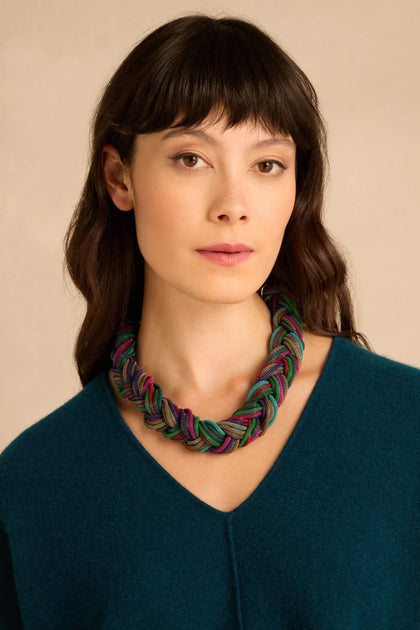 A Braided Rainbow Chain Necklace featuring chunky, interwoven strands in shades of green, purple, and blue worn around a person’s neck.