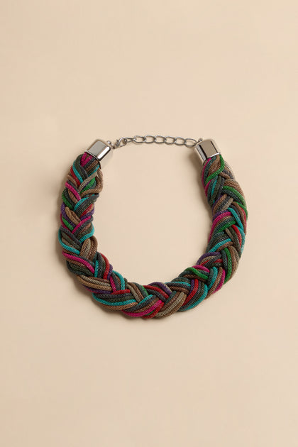 The Braided Rainbow Chain Necklace is a chunky collar made of interwoven mesh cords in shades of green, blue, pink, and metallic brown, featuring silver-tone end caps and a chain extender.