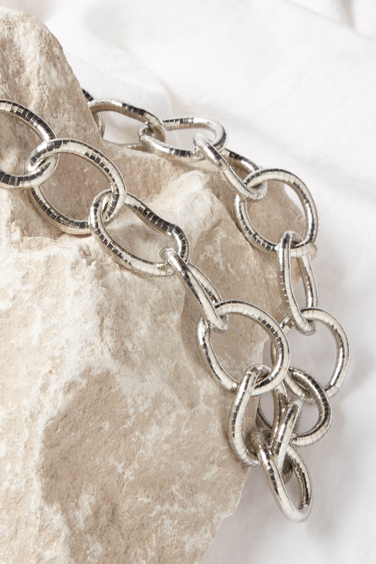 A classic silver chain Long Silver Links Necklace with long silver links, sitting on top of a rock.