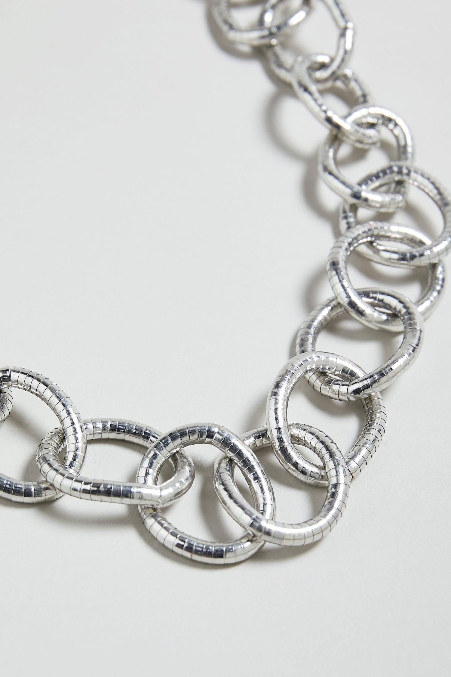 Close-up of the Long Links Necklace, an oversized silver chain featuring large, textured interlocking circular links, displayed against a plain light background.