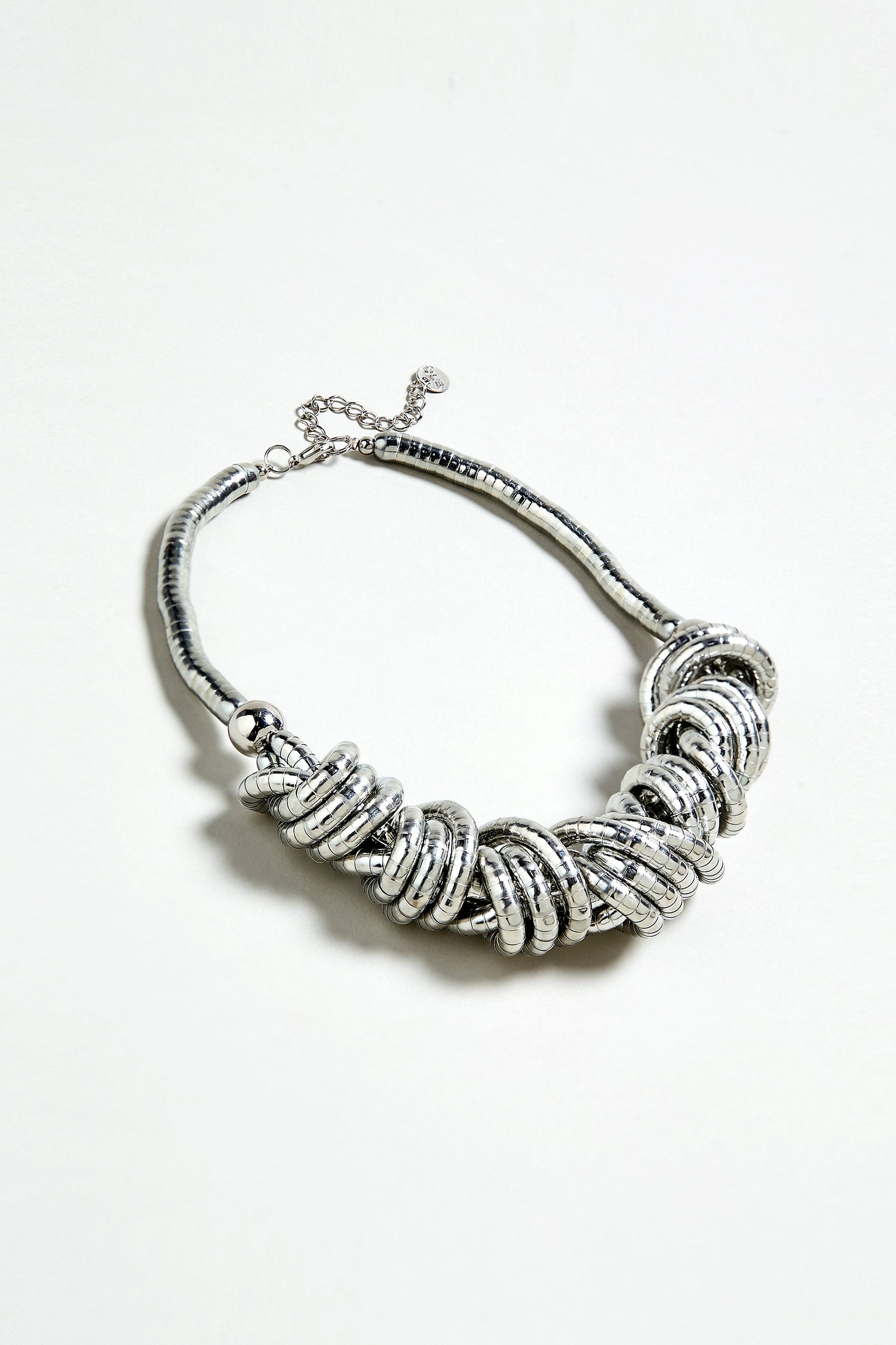 The Woven Silver Necklace features chunky interlocking rings in a clustered design, showcased against a plain white background.