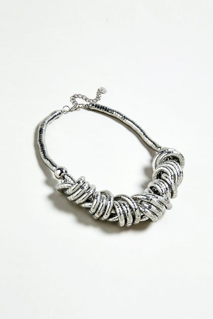 The Woven Silver Necklace features chunky interlocking rings in a clustered design, showcased against a plain white background.