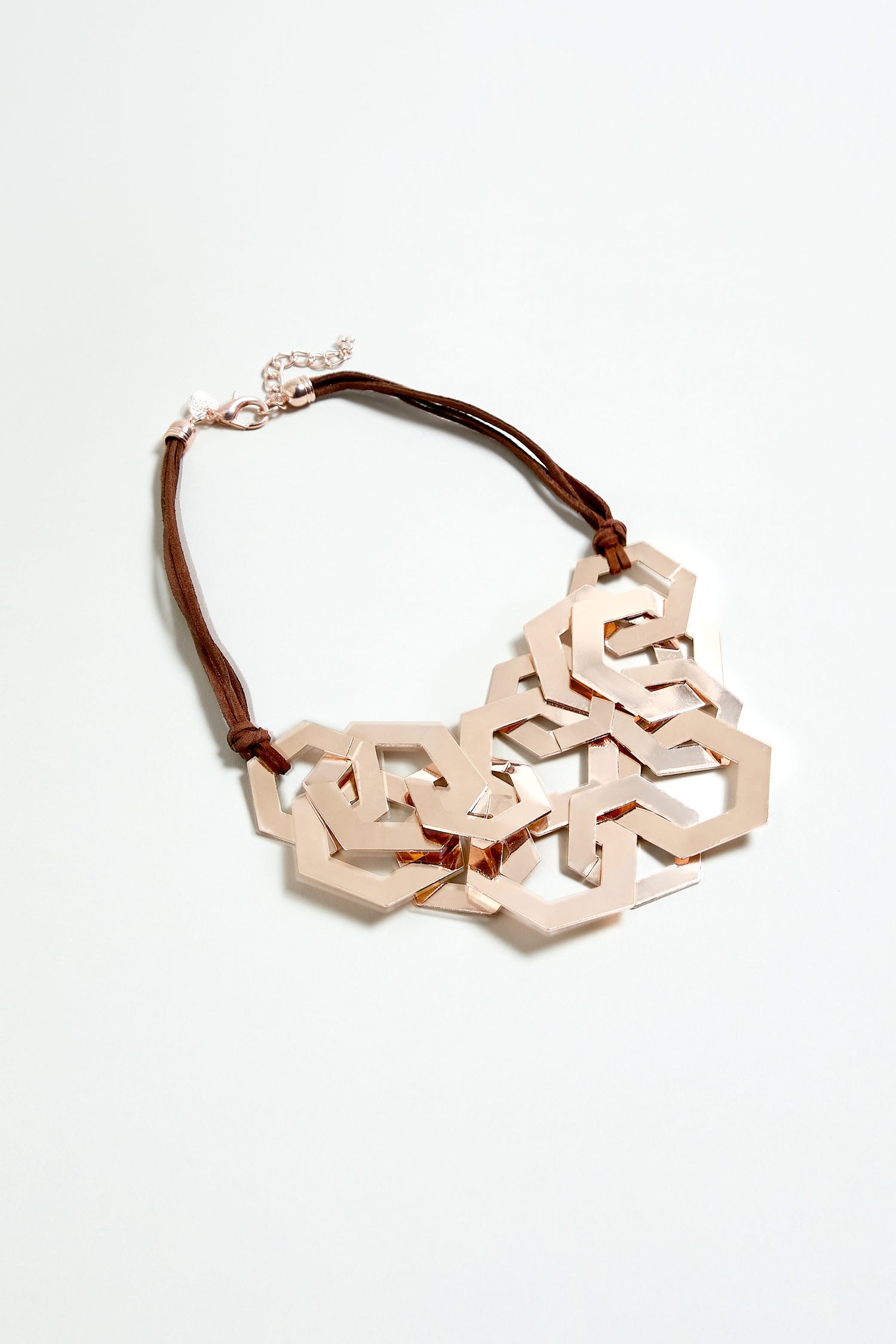 The Hexagon Links Necklace features geometric gold metal links on a brown cord with an adjustable clasp, shown on a light background.
