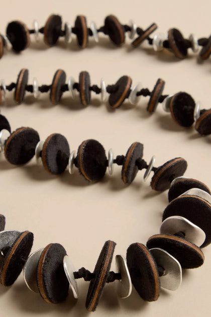 Velvet Detail Disc Necklace consisting of a long strand of alternating dark velvet discs and silver-tone metal rings on a black cord.