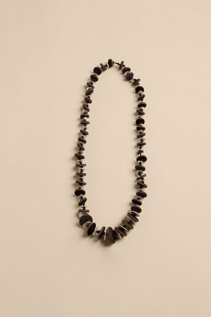 Velvet Detail Disc Necklace consisting of a long cord with alternating small brown circular discs and larger dark brown textured velvet discs.