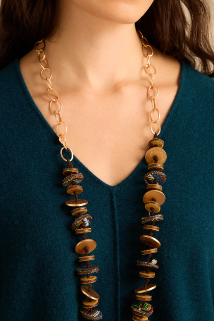 Textured Disc Necklace featuring a long gold chain with a strand of alternating wooden and textured, patterned fabric discs.