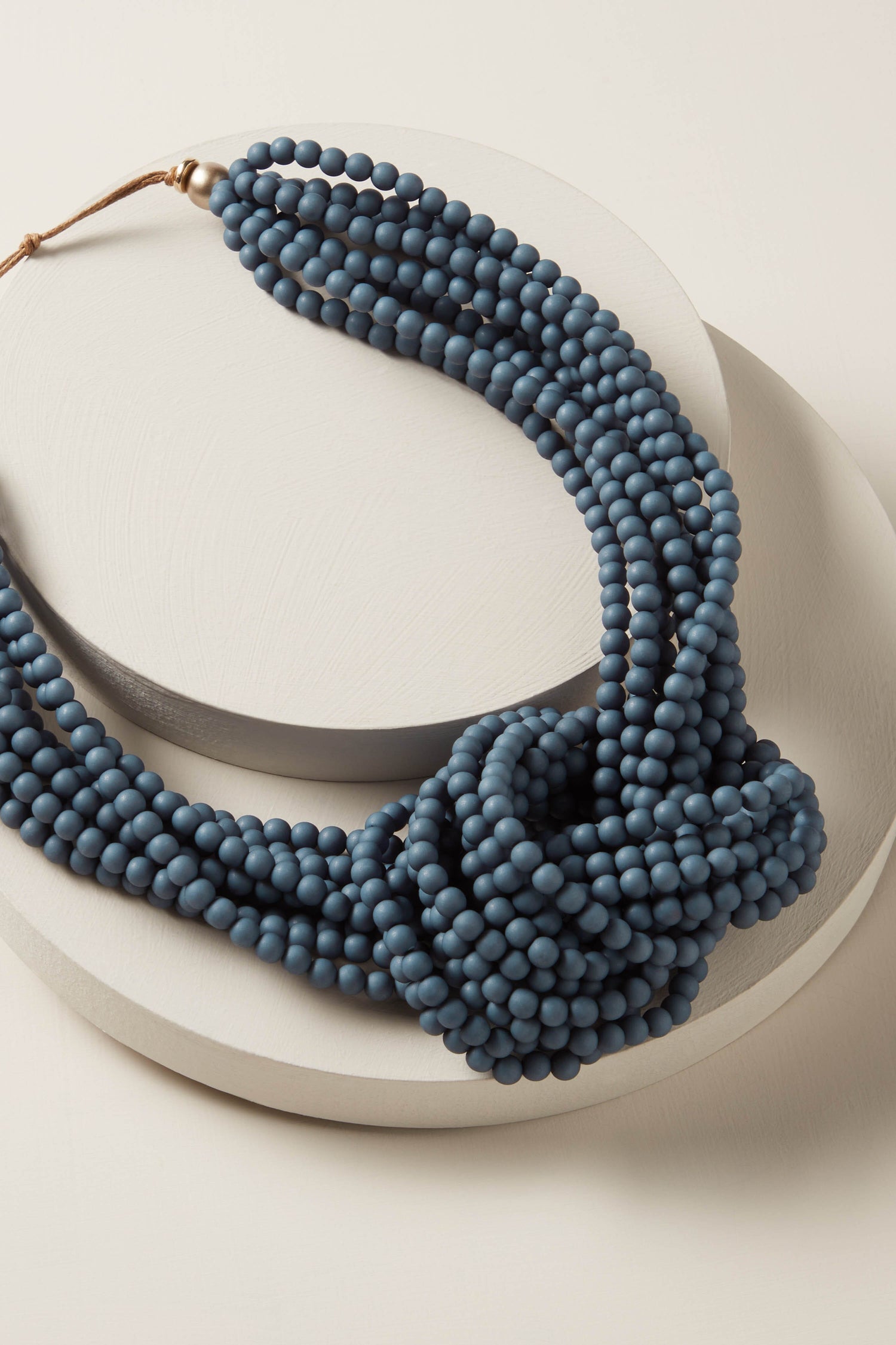 A blue Knotted Bead Necklace with metallic accents on a white surface.