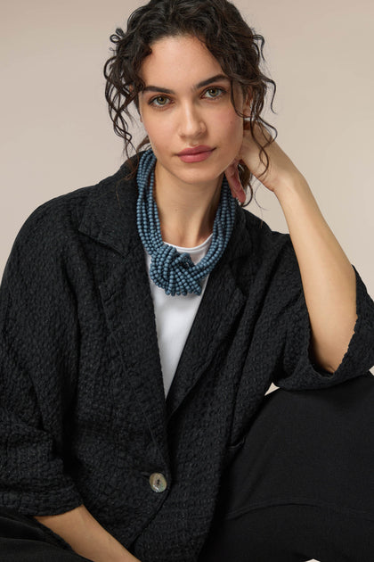 A woman wearing a black jacket and a Knotted Bead Necklace.