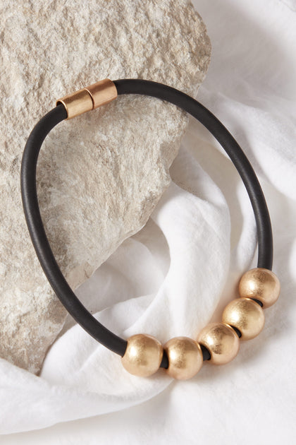 A Hammered Gold Spheres Necklace with black cord.