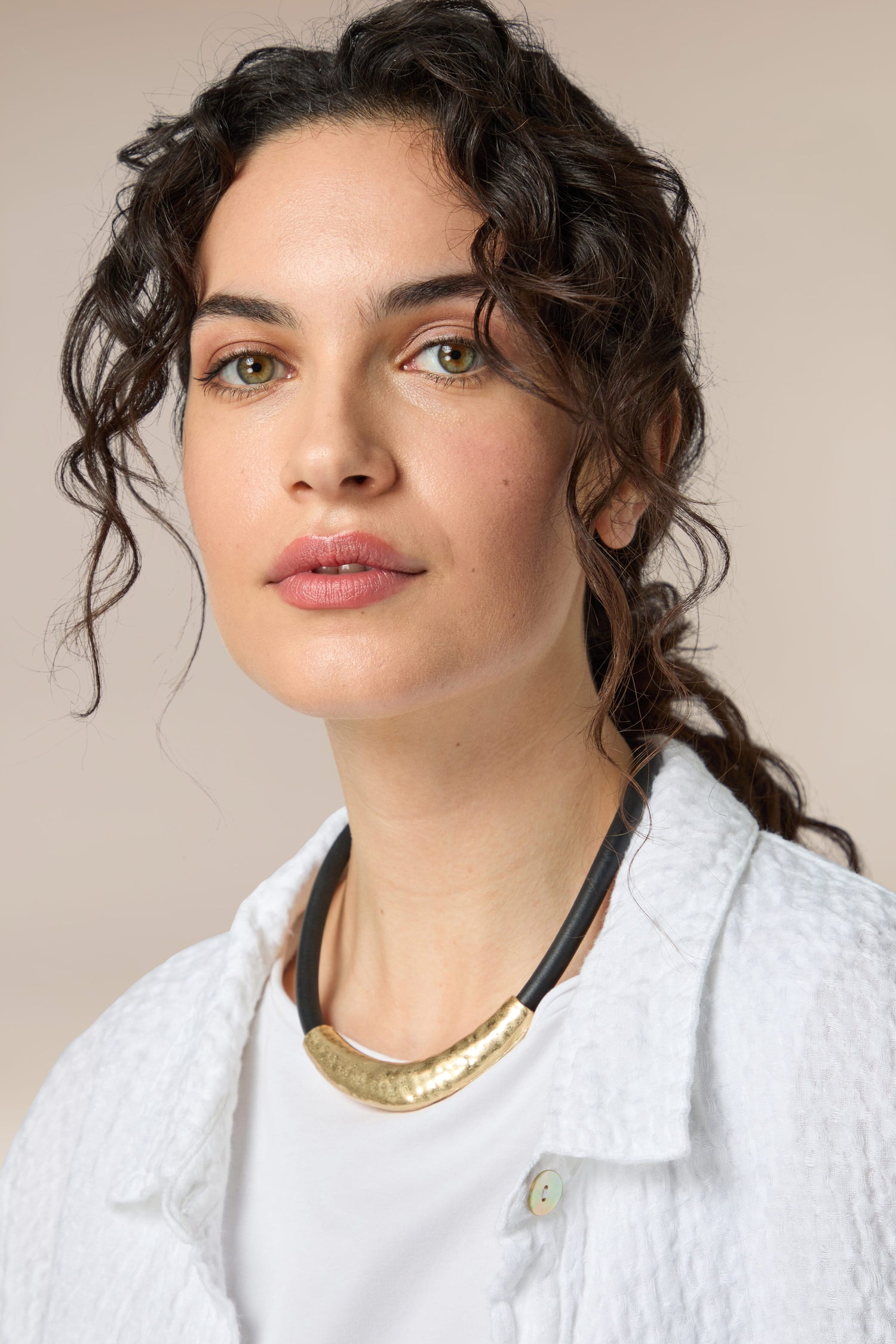 A woman with curly hair wearing a Hammered Necklace.