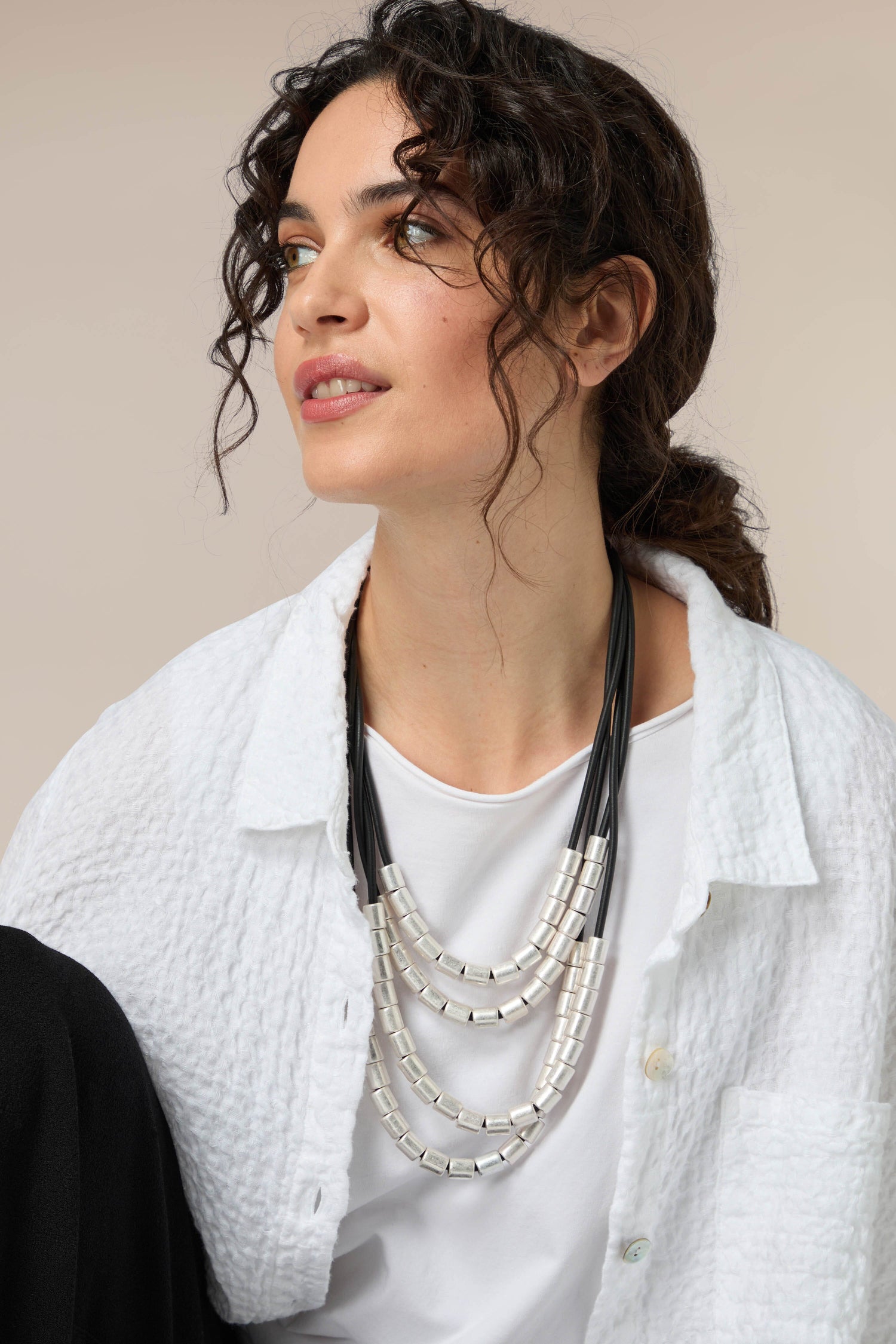 A woman wearing a Layered Silver Spheres Necklace and white shirt.