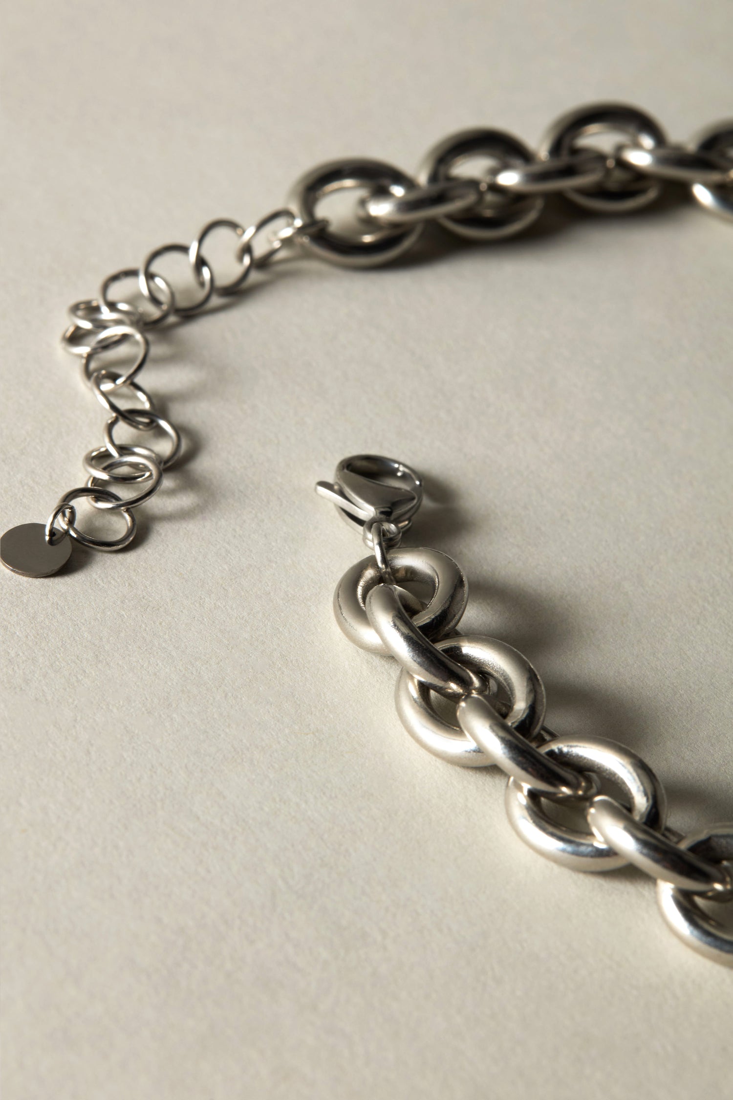 A close-up of the Short Silver Chain Necklace with a lobster clasp on a light surface, highlighting its versatile design for any jewelry collection.