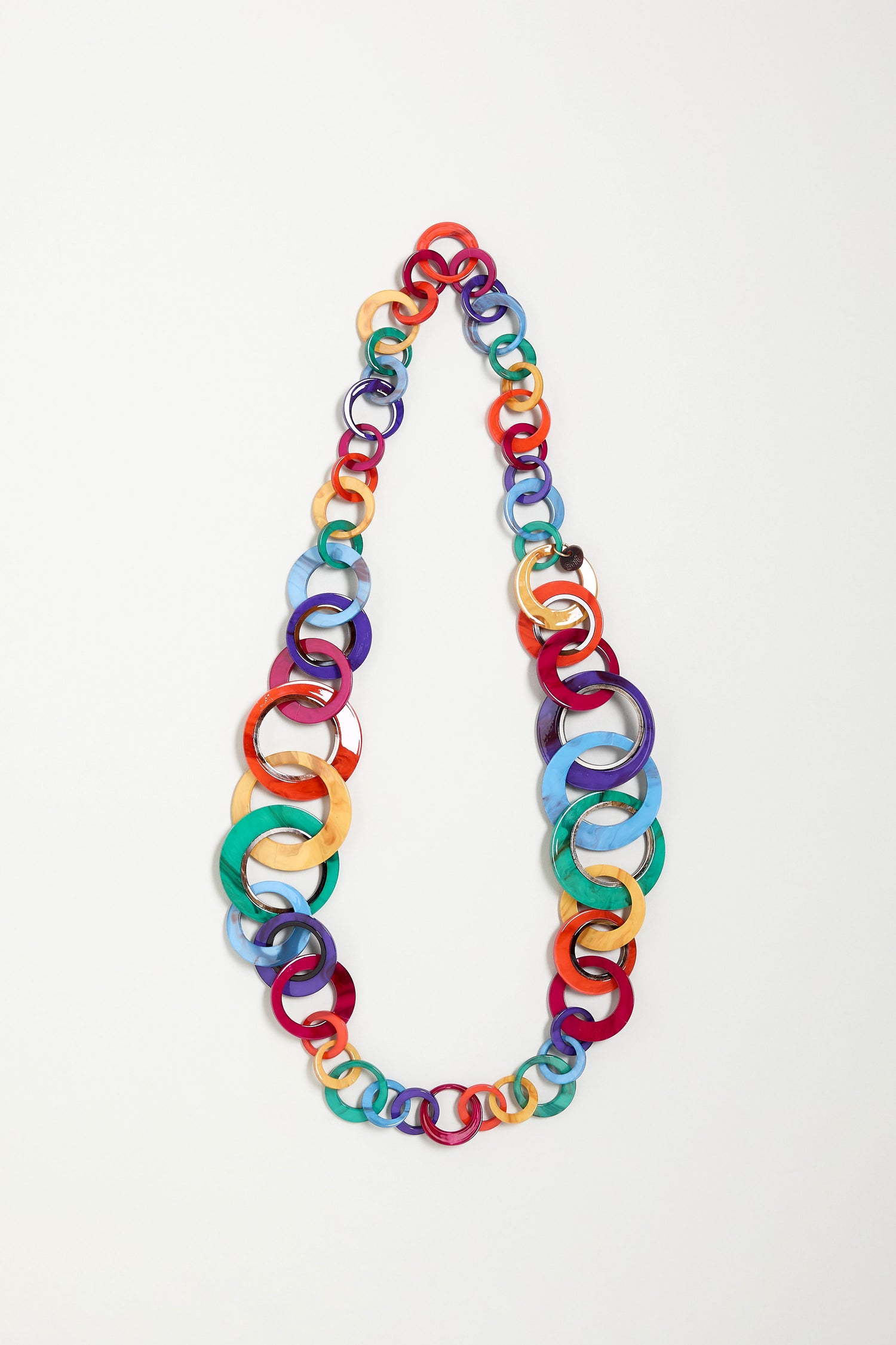 The Rainbow Resin Hoops Necklace showcases interlinked circular acrylic rings in bright colors on a white background—ideal for fans of sculptural, colorful accessories.