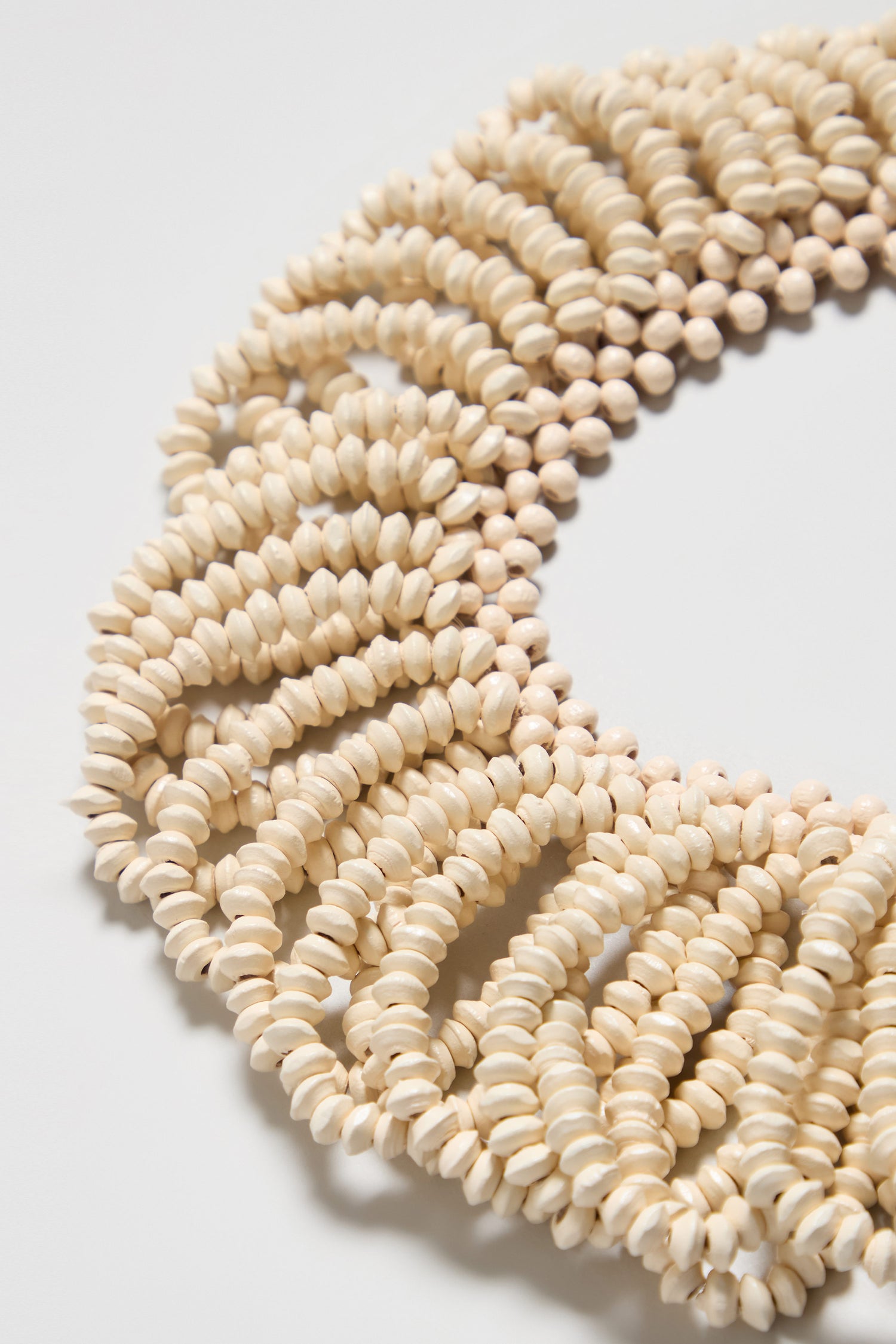 Close-up of the Natural Beaded Collar Necklace, showcasing multiple strands of small, light seashell beads arranged in a dense, textured pattern.