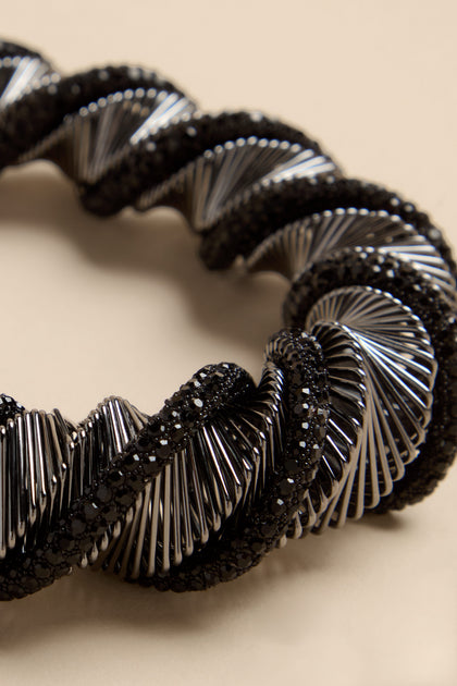 The Midnight Helix necklace features a coiled design with alternating sections of silver-toned metal bars and pavé black stones.