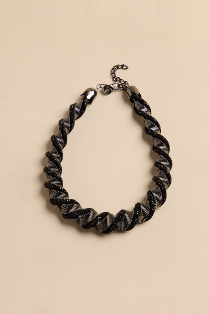 The Midnight Helix necklace features a twisted statement design with alternating bands of black crystal beads and metallic silver ribbing.